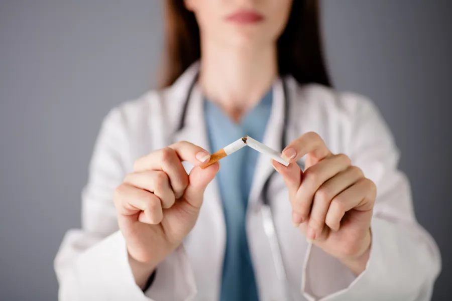 Person in lab coat breaking cigarette in half
