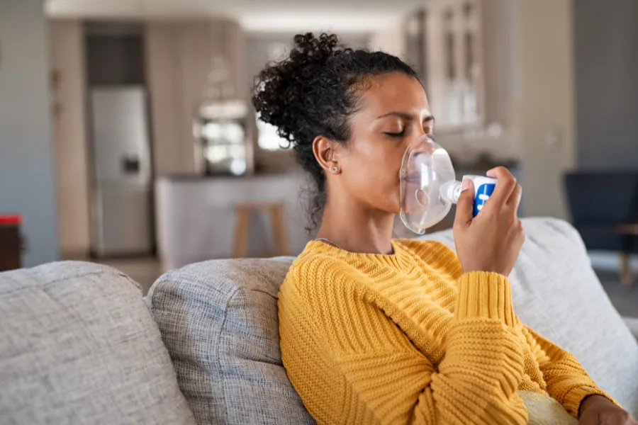 Woman on couch with assisted plastic device over her mouth